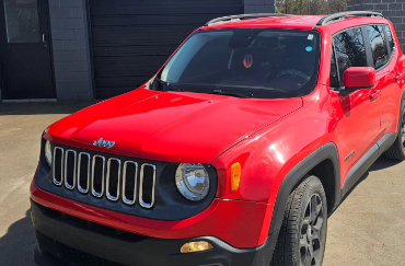 A red Jeep car with tinted windows